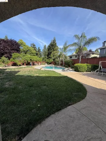 Expansive backyard featuring a central swimming pool, surrounding patio, and lush lawn areas