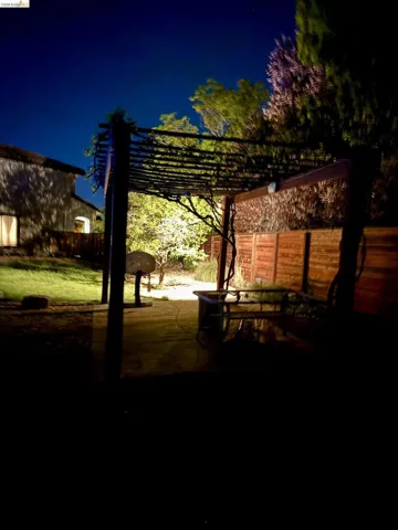 Yard at twilight featuring a fenced backyard, a pergola, and a patio