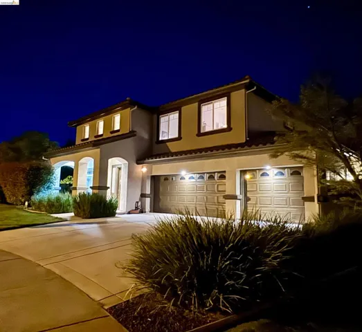 View of front facade featuring a garage, driveway, and stucco siding