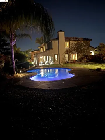 Back of house at twilight featuring a patio, stucco siding, and a chimney