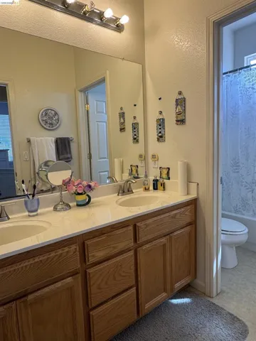 Dual vanity with integrated sinks, light wood-finish cabinetry, and a light-toned countertop