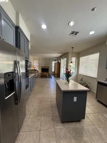 Spacious kitchen featuring an island with a light-toned countertop, stainless steel appliances, recessed lighting, and tile flooring