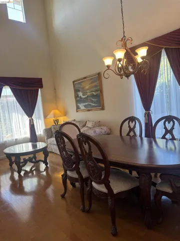 Formal dining space featuring wood-finish flooring, a decorative chandelier, and high ceilings