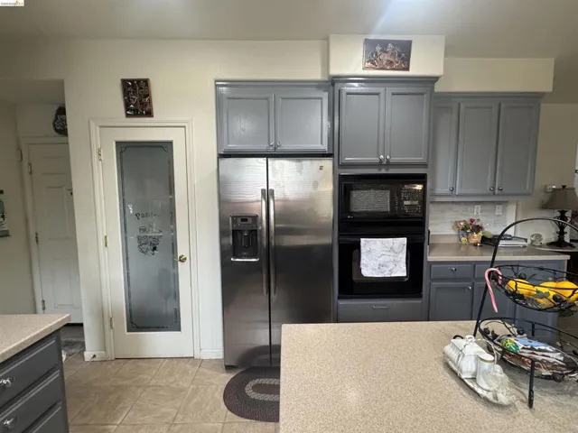 Kitchen featuring gray cabinets, black appliances, backsplash, and light tile patterned floors