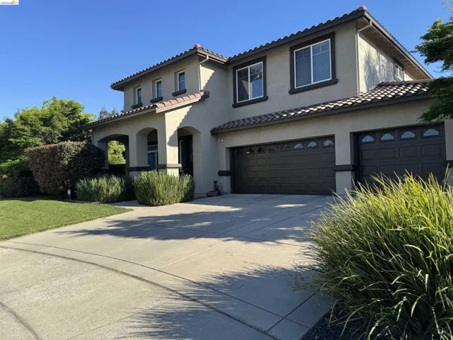 Mediterranean / spanish home with concrete driveway, stucco siding, an attached garage, and a tiled roof
