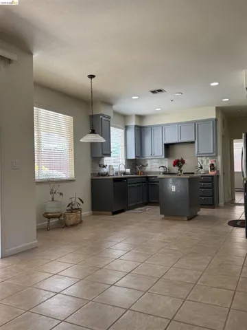 Open-concept kitchen featuring gray cabinetry, a central island, recessed lighting, and tile flooring