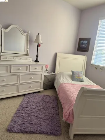 Carpeted room with a window featuring horizontal blinds