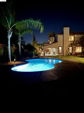 Pool at night featuring an outdoor pool and a patio area
