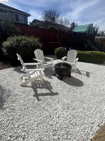 Fenced backyard featuring an outdoor fire pit and a playground