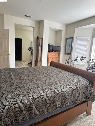 Carpeted flooring in a room featuring a window with blinds, an architectural niche, and an open doorway to an adjacent area with tile flooring