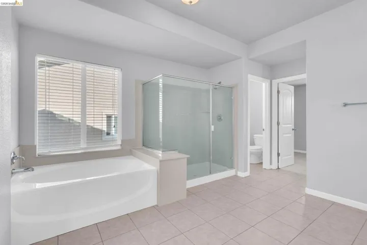 Full bathroom with a stall shower, light tile patterned floors, and a bath