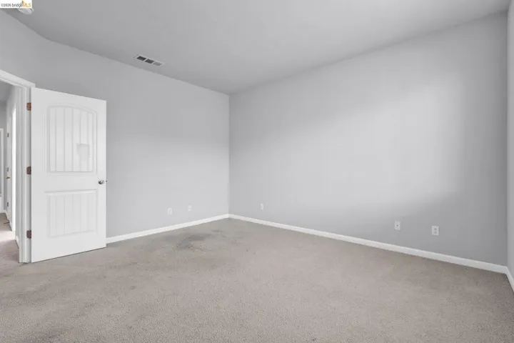 Empty room with light colored carpet and baseboards
