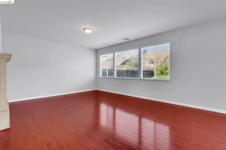 Spare room featuring dark wood-style flooring and baseboards