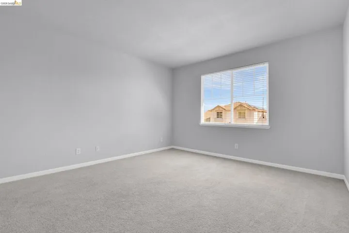 Empty room with light colored carpet and baseboards
