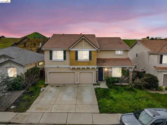 Traditional-style house with stucco siding, a garage, a tile roof, and driveway