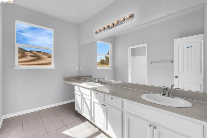 Full bathroom with double vanity and light tile patterned floors