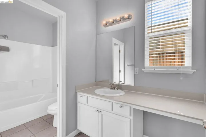 Bathroom featuring vanity, light tile patterned floors, and shower / washtub combination