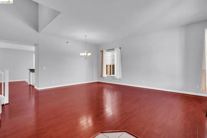 Empty room with dark wood finished floors and hanging lights