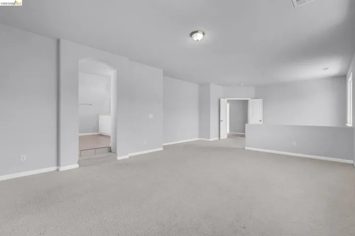 Spare room with light colored carpet and arched walkways