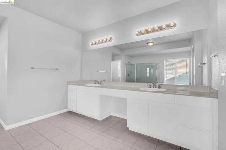 Full bath featuring double vanity, a stall shower, and light tile patterned floors