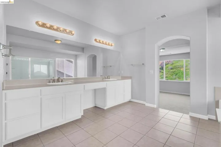 Full bathroom featuring double vanity, a shower stall, and light tile patterned floors