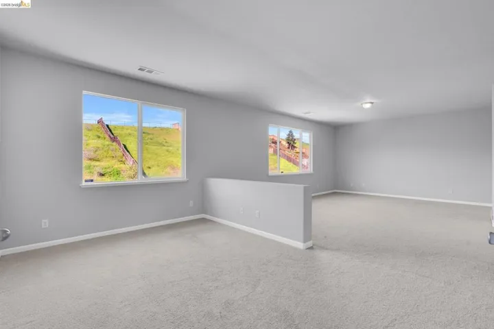 Unfurnished room featuring light carpet and plenty of natural light