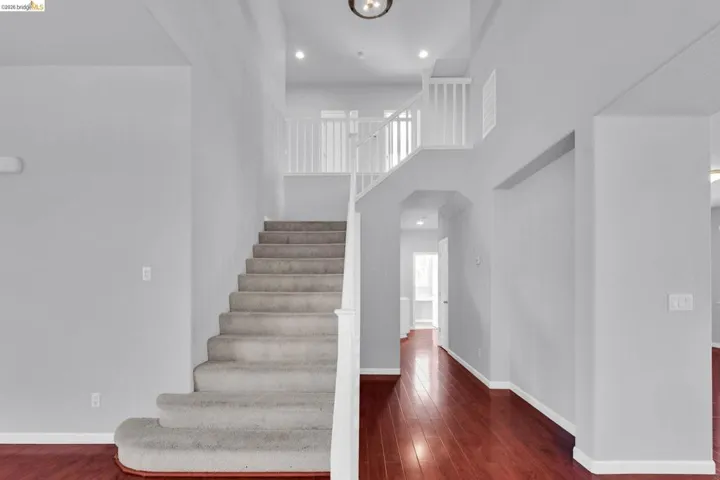 Stairs with wood-type flooring, a high ceiling, and recessed lighting