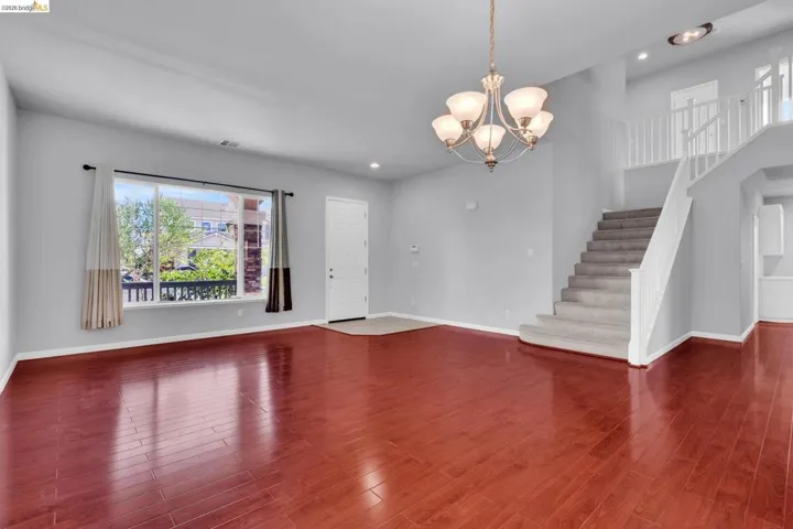 Unfurnished living room with suspended lighting and dark wood-style flooring