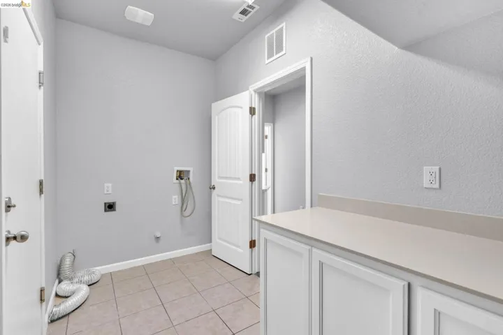 Laundry room with gas dryer hookup, hookup for a washing machine, a textured wall, hookup for an electric dryer, and light tile patterned floors