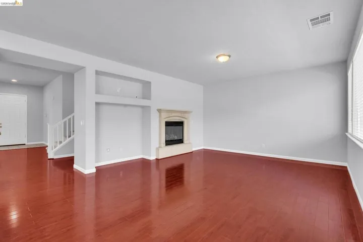 Unfurnished living room featuring dark wood-type flooring and a fireplace
