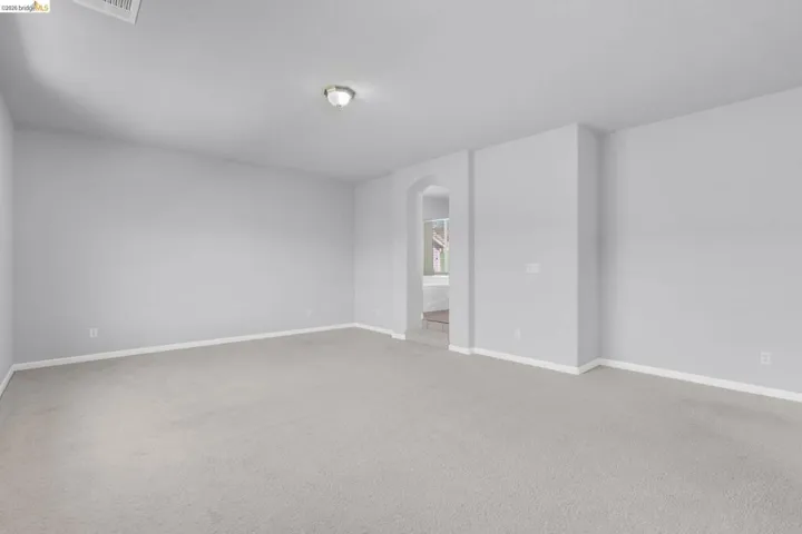 Unfurnished room with arched walkways and light colored carpet
