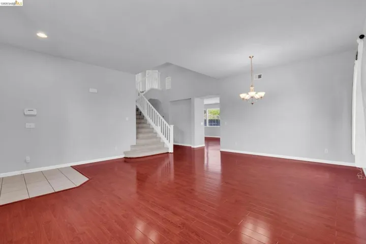 Unfurnished living room featuring suspended lighting and dark wood finished floors