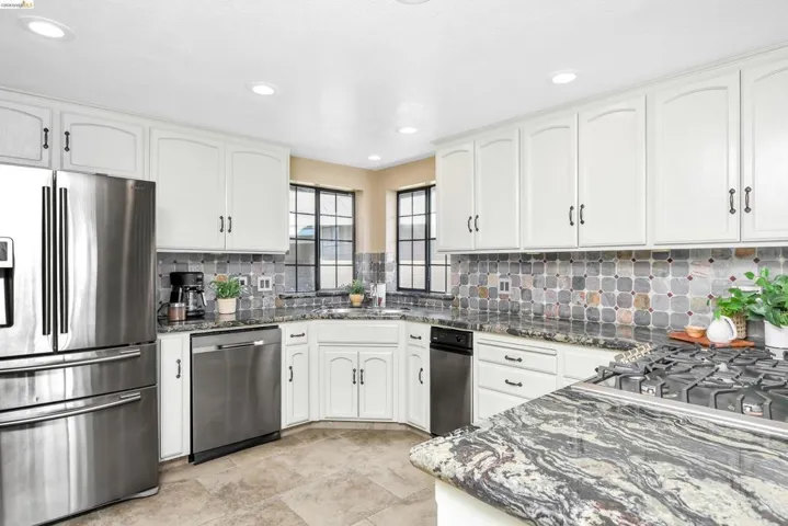 Kitchen with stainless steel appliances, dark stone countertops, white cabinetry, tasteful backsplash, and recessed lighting