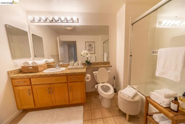 Full bathroom with vanity, enclosed tub / shower combo, and light tile patterned floors
