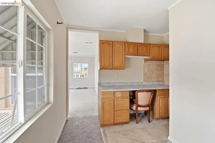 unfurnished office featuring light colored carpet, crown molding, and built in study area