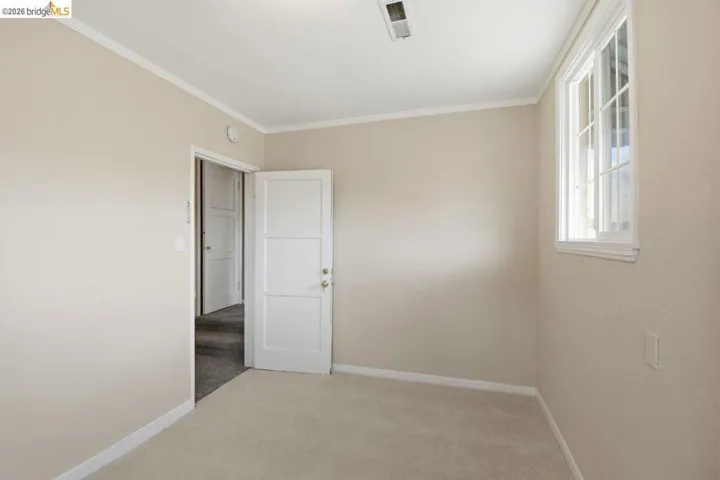 spare room with ornamental molding and light colored carpet