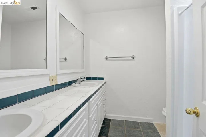 bathroom with double vanity and dark tile patterned flooring