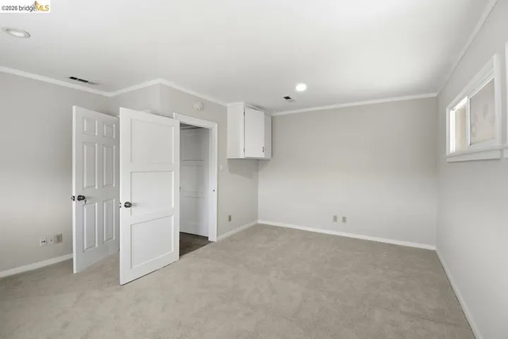 unfurnished bedroom with a spacious closet, light carpet, and crown molding