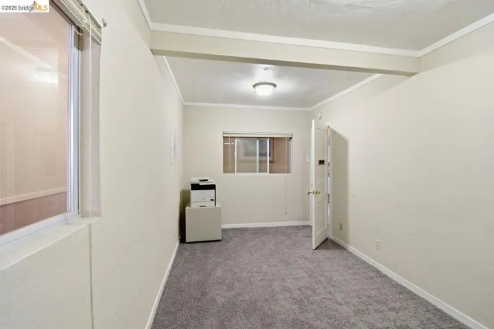 carpeted empty room featuring baseboards and crown molding