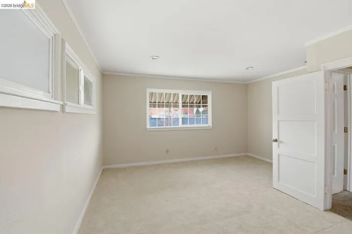 unfurnished room with light colored carpet and crown molding