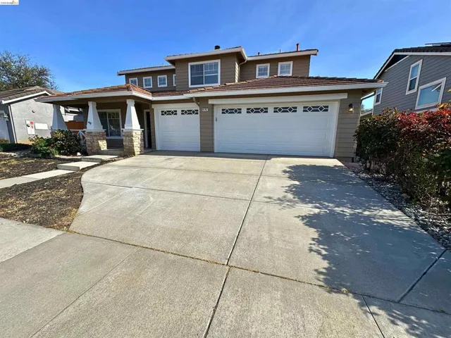 View of front of house with concrete driveway, covered porch, an attached garage, and a tiled roof