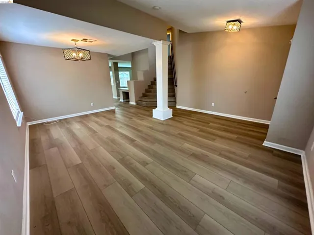 Unfurnished living room featuring light wood finished floors and baseboards