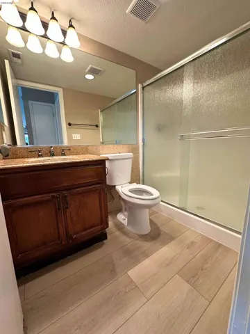 Bathroom featuring vanity, a shower stall, a textured ceiling, and light wood-type flooring