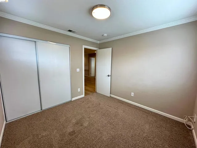 Unfurnished bedroom with carpet, crown molding, and a closet