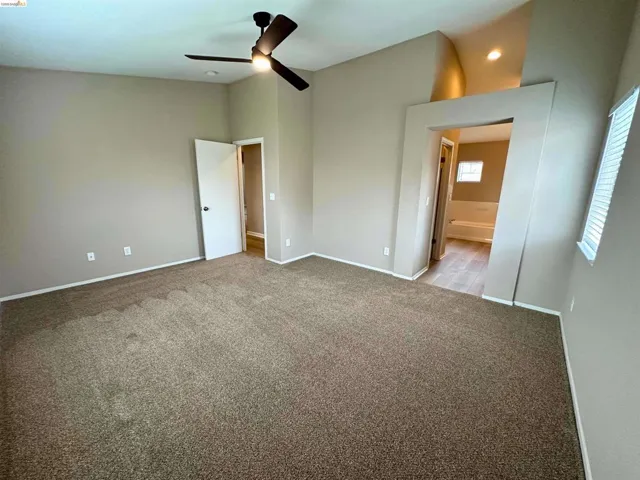 Unfurnished bedroom with light colored carpet, connected bathroom, a ceiling fan, and recessed lighting