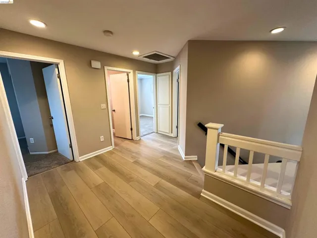 Hall with an upstairs landing, light wood-style floors, and recessed lighting