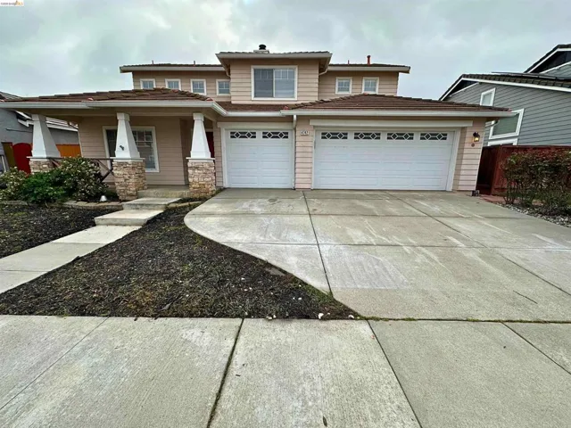 View of front of home with concrete driveway, covered porch, and an attached garage