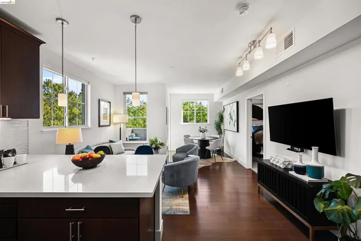 Kitchen featuring dark wood finish cabinetry, open floor plan, dark wood-style floors, light stone counters, and a peninsula