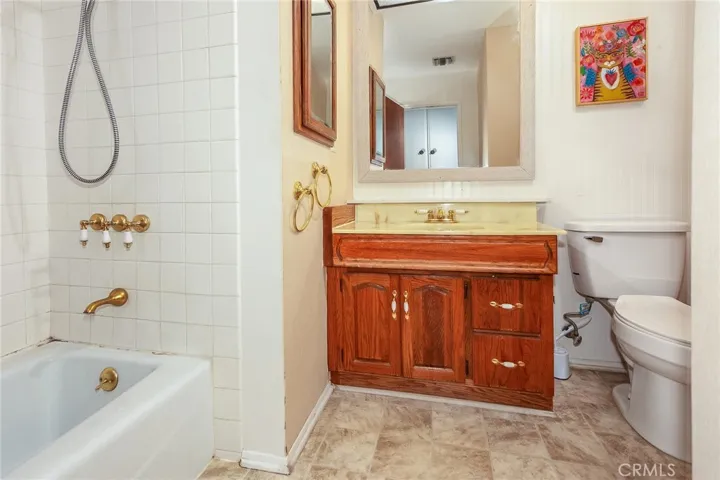 The guest bathroom features a single vanity, framed dressing mirror, separate medicine cabinet, wainscoting detail, and a tiled tub and shower combination.