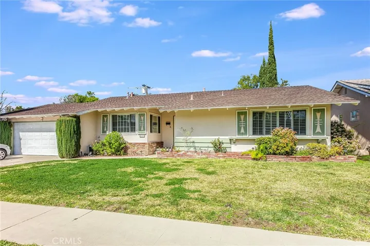 Located on a quiet street in Canoga Park, this inviting 3-bedroom, 2-bathroom home offers 1,316 square feet of comfortable living space on an expansive 7,445 square foot lot. The home greets you with attractive curb appeal featuring a manicured front lawn, colorful raised brick planters, trimmed hedges, and a covered entry. Updated mullioned windows enhance the exterior character while bringing in beautiful natural light.